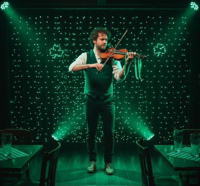 Fiddler performing in front of green lights